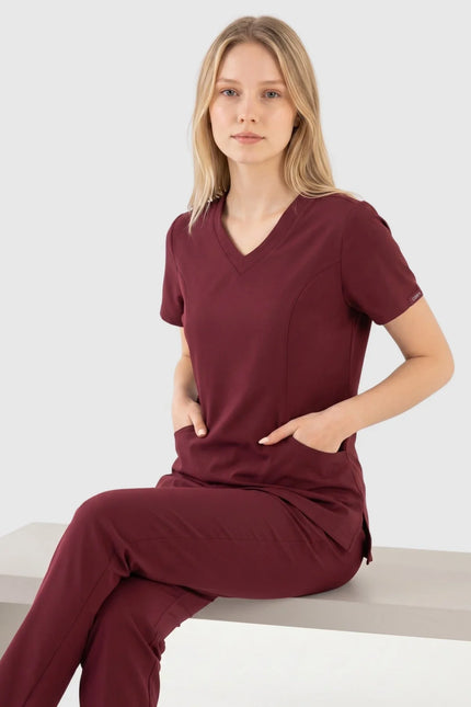 Bordo renkli kadın medikal forma takımı giyen model, damla yaka ve kısa kollu tasarım.